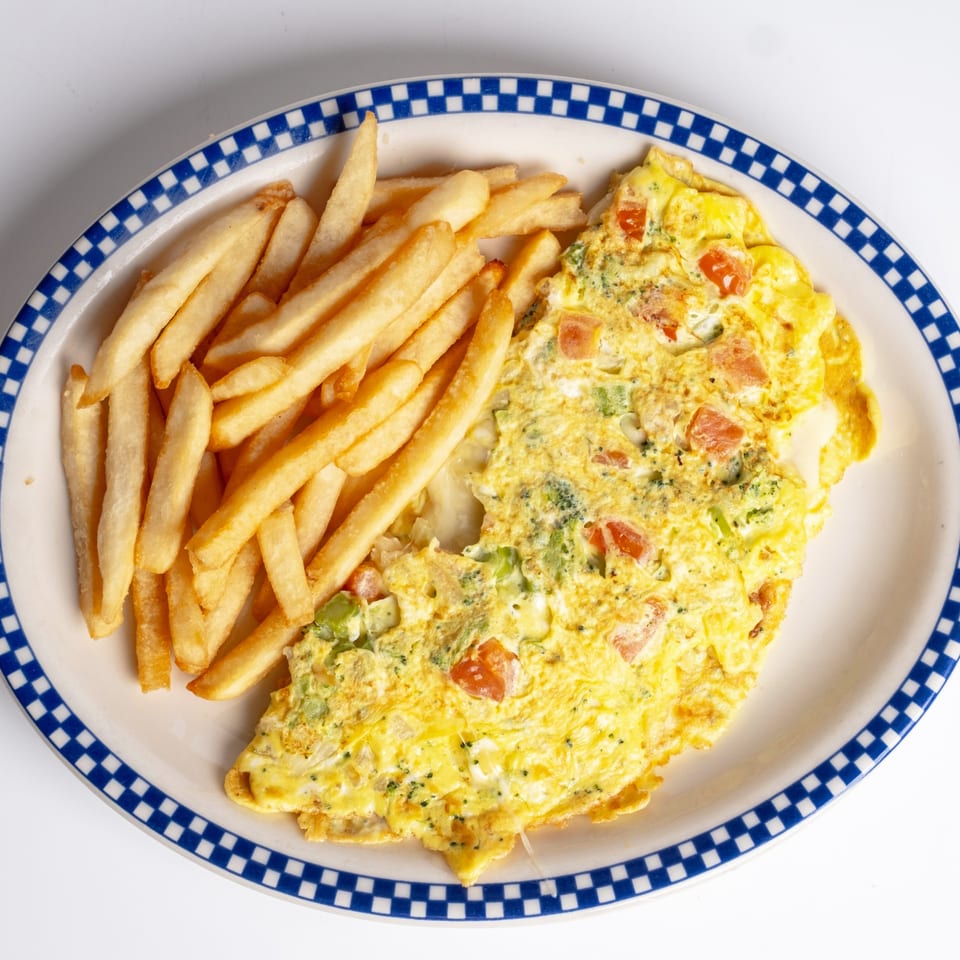 A Sunny Side Diner omelet with tomatoes, broccoli, and cheese, served with golden french fries.
