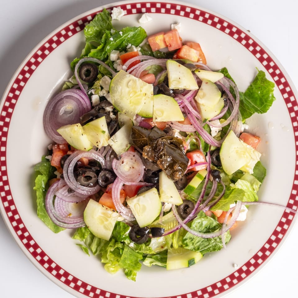 A fresh Greek salad from Sunny Side Diner with lettuce, tomatoes, cucumbers, olives, onions, and feta.